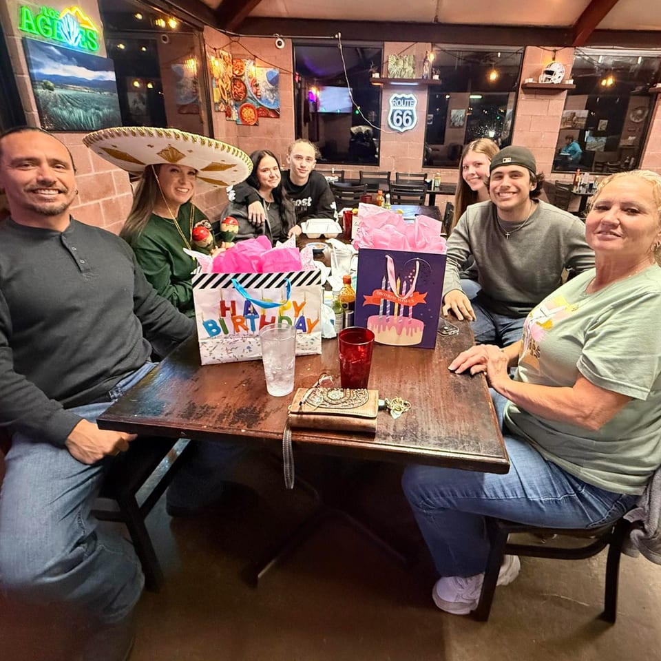 A group of seven people celebrating a birthday at a table in Los Agaves Mexican Restaurant.