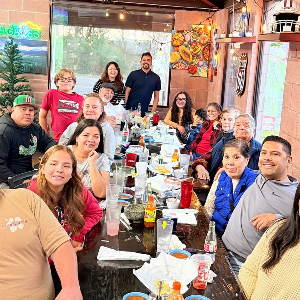 A large family gathers around a long table, enjoying a meal at Los Agaves Mexican Restaurant.